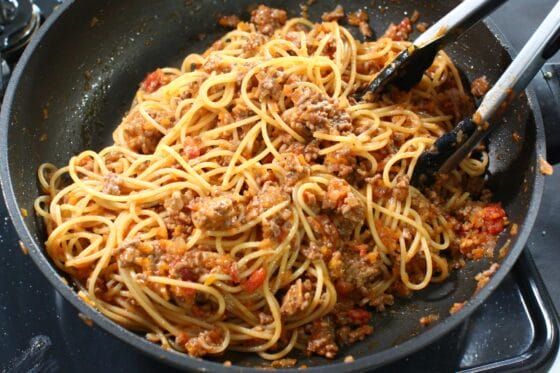 茹でたスパゲッティをボロネーゼソースに加え、茹で汁と一緒に中火で絡める