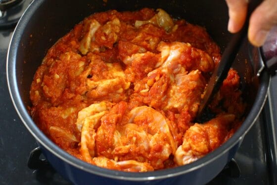スパイスを炒めたトマトソースに鶏もも肉を加え、全体に絡める