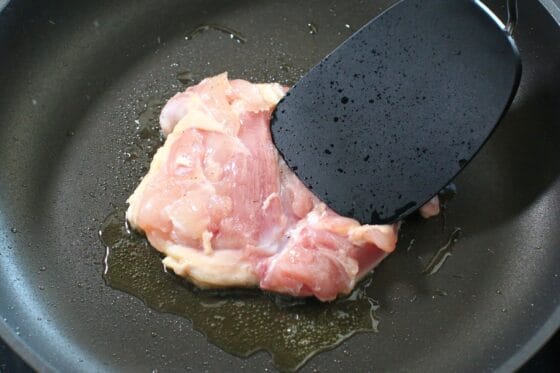 鶏もも肉を皮目から中火で焼き、ヘラで軽く押さえる