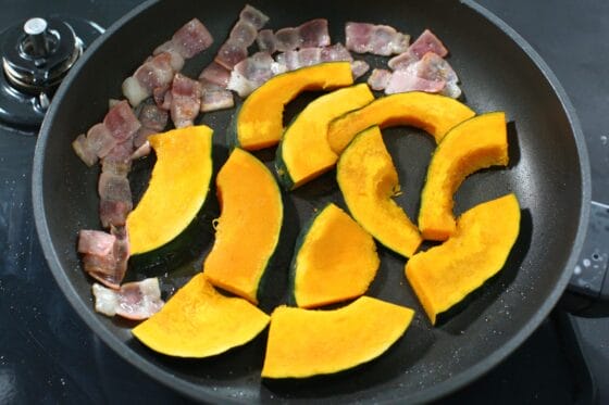 炒めたベーコンにレンジ加熱したかぼちゃを加えて焼き始める