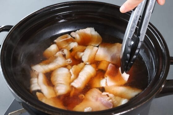 きのこ鍋の醤油ベースのつゆが煮立ったら、豚バラ肉を1枚ずつ広げて加える