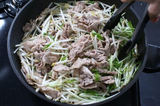 豚肉にもやしと水菜の茎を加えて強めの中火で炒める