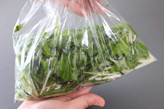 水菜の漬物の材料をポリ袋に入れ、全体をやさしくもんで調味料をなじませる