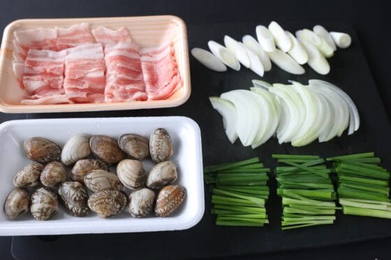 あさりを用意して、豚バラ肉、玉ねぎ、長ねぎ、ニラを切って準備する