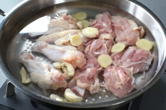 鍋に鶏肉とにんにく、生姜を入れ、水と酒を注いで中火にかける
